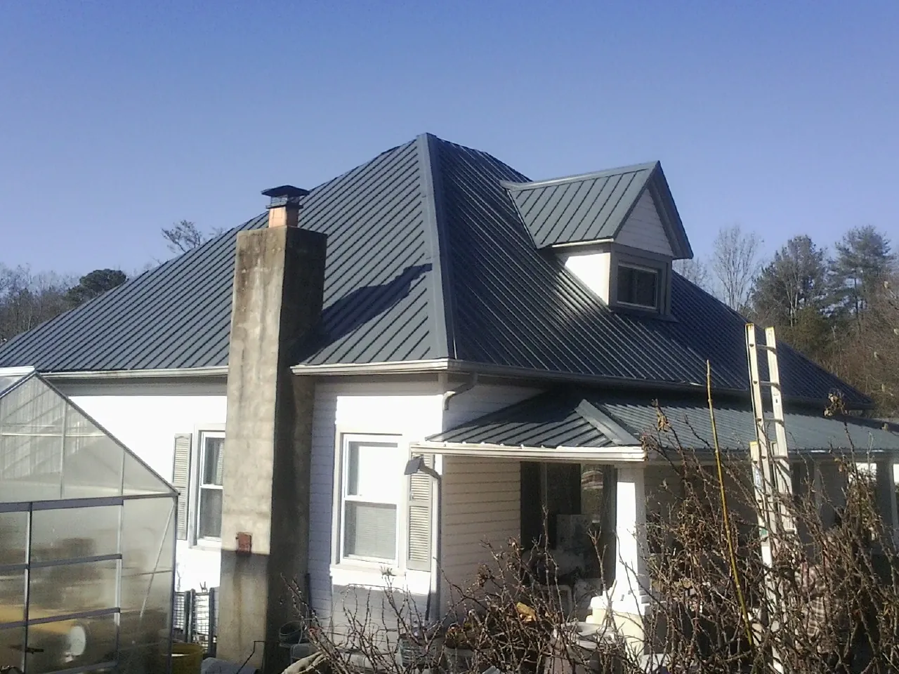 Dark blue standing seam metal roof on a white farmhouse with dormer — Slate & Tile Roof Repair by Roofing Brothers in Mattawana