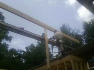 Carpenter setting a ridge beam over a new addition frame — Ice Dam Removal by Roofing Brothers in Mattawana