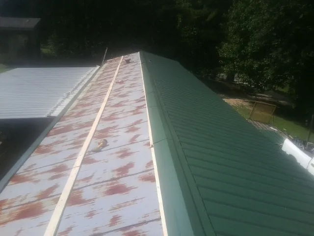 Old rusted panels beside newly installed green metal roofing — Wind Damage Roof Repair by Roofing Brothers in Mattawana