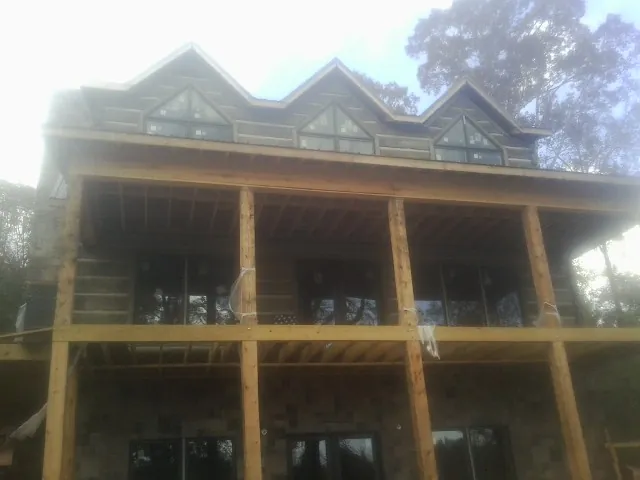 Dormers and porch framing on a large log home under construction — Roof Coating work by our crew in Mattawana