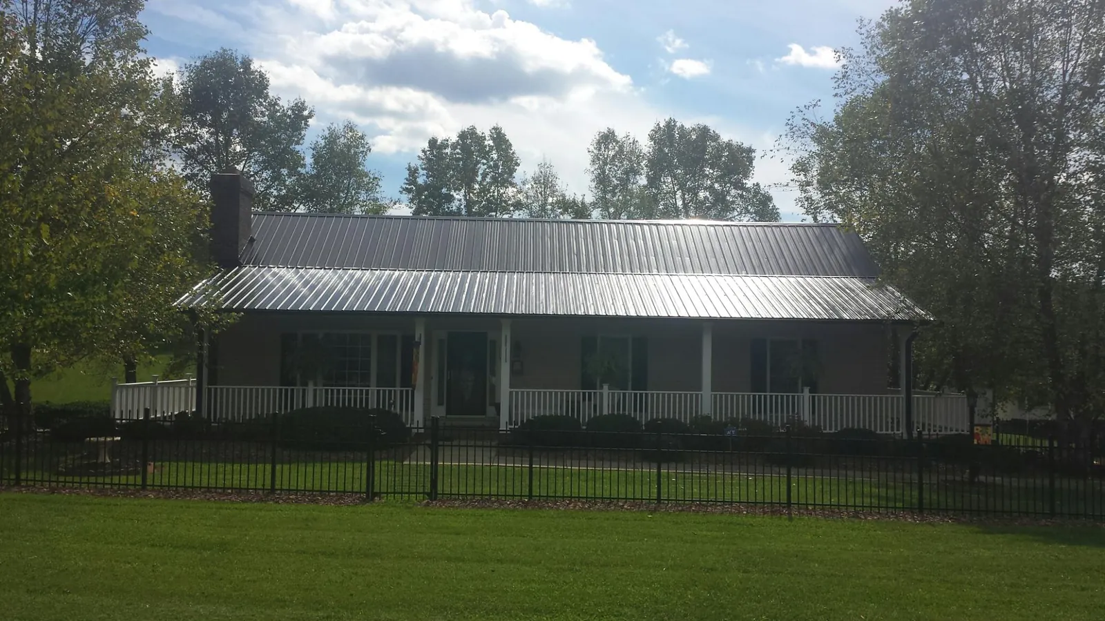 Gray metal roof on a brick ranch with a full width front porch — Gutter Guard Installation work by our crew in Mattawana