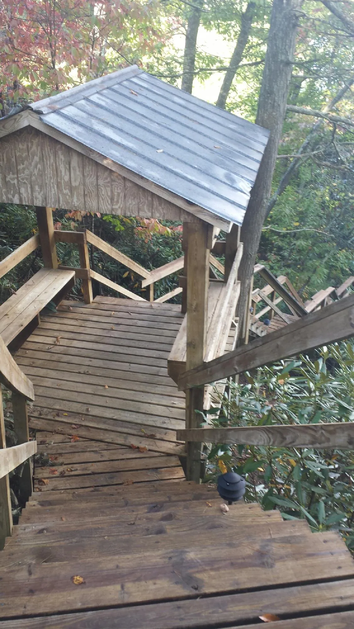 Metal roofed shelter over wooden steps on a wooded walkway — Skylight Repair & Installation work by our crew in Mattawana